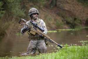 Accuracy International AX ELR Dark Earth 27-inch rifle, full-length view in an official manufacturer outdoor photograph